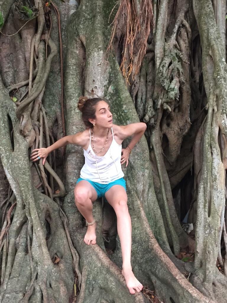 Dila Yumurtacı seated among the roots of a large tree