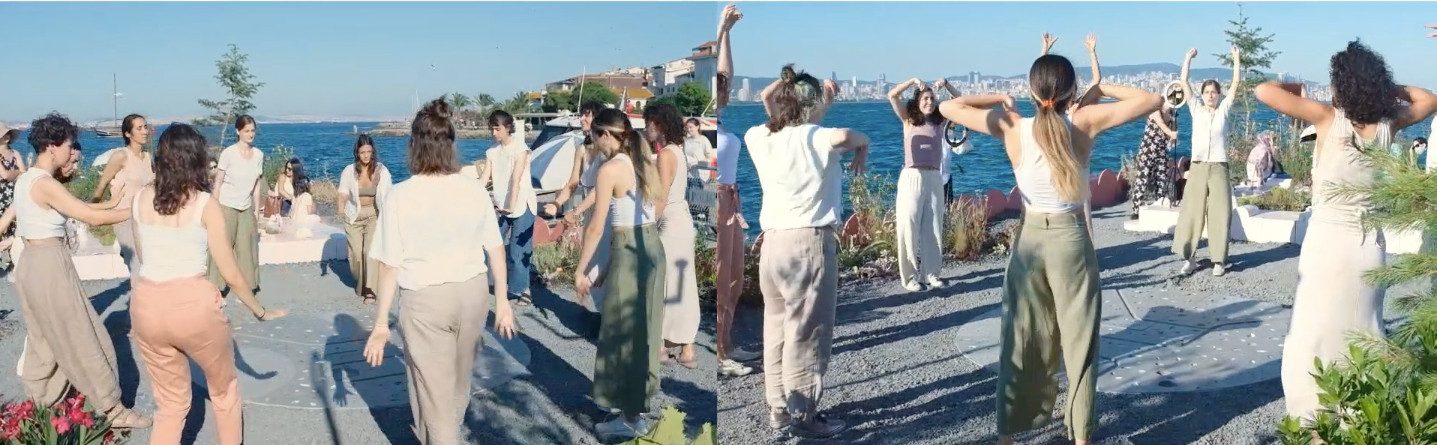 Participants moving with raised arms on a seaside terrace, the city across the water