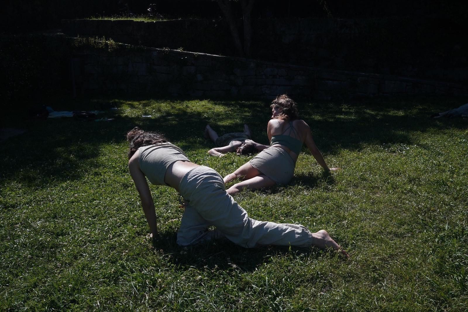 Two performers lying on the grass in deep shade, Serralves