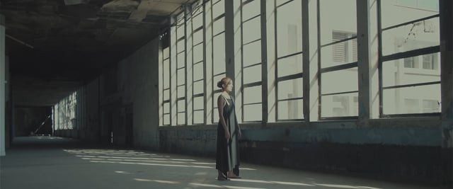 A dancer with arms raised in the sunlit hall
