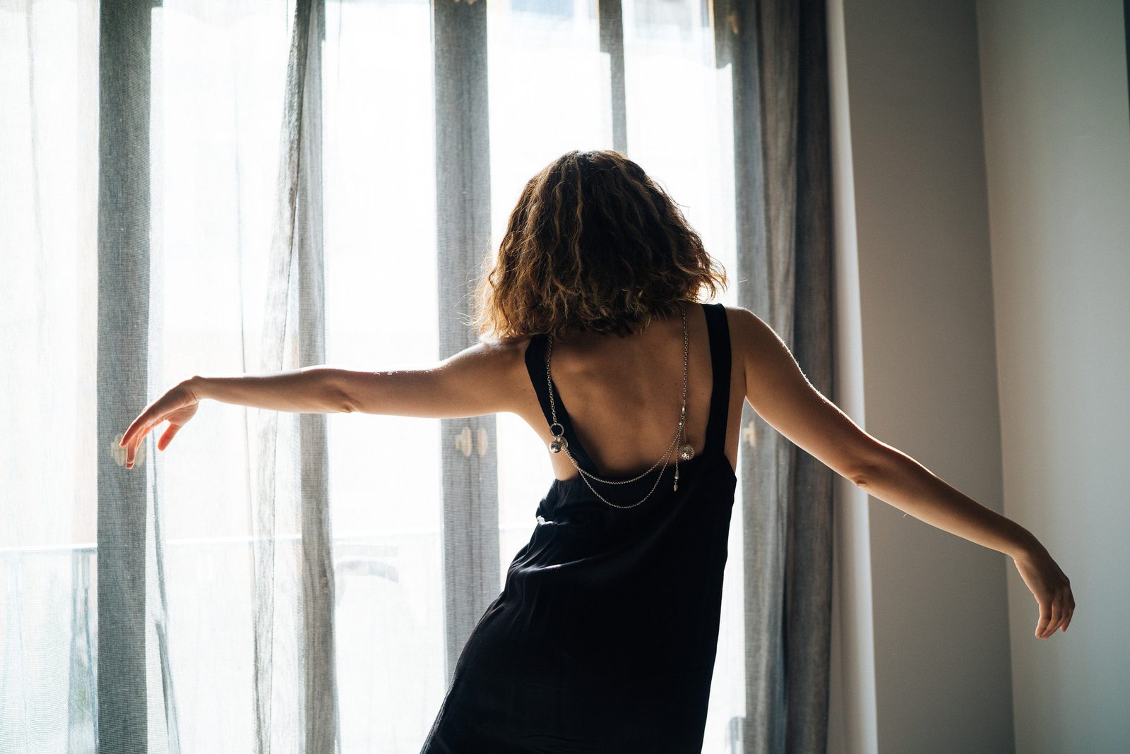 Dila with arms spread in front of the curtains