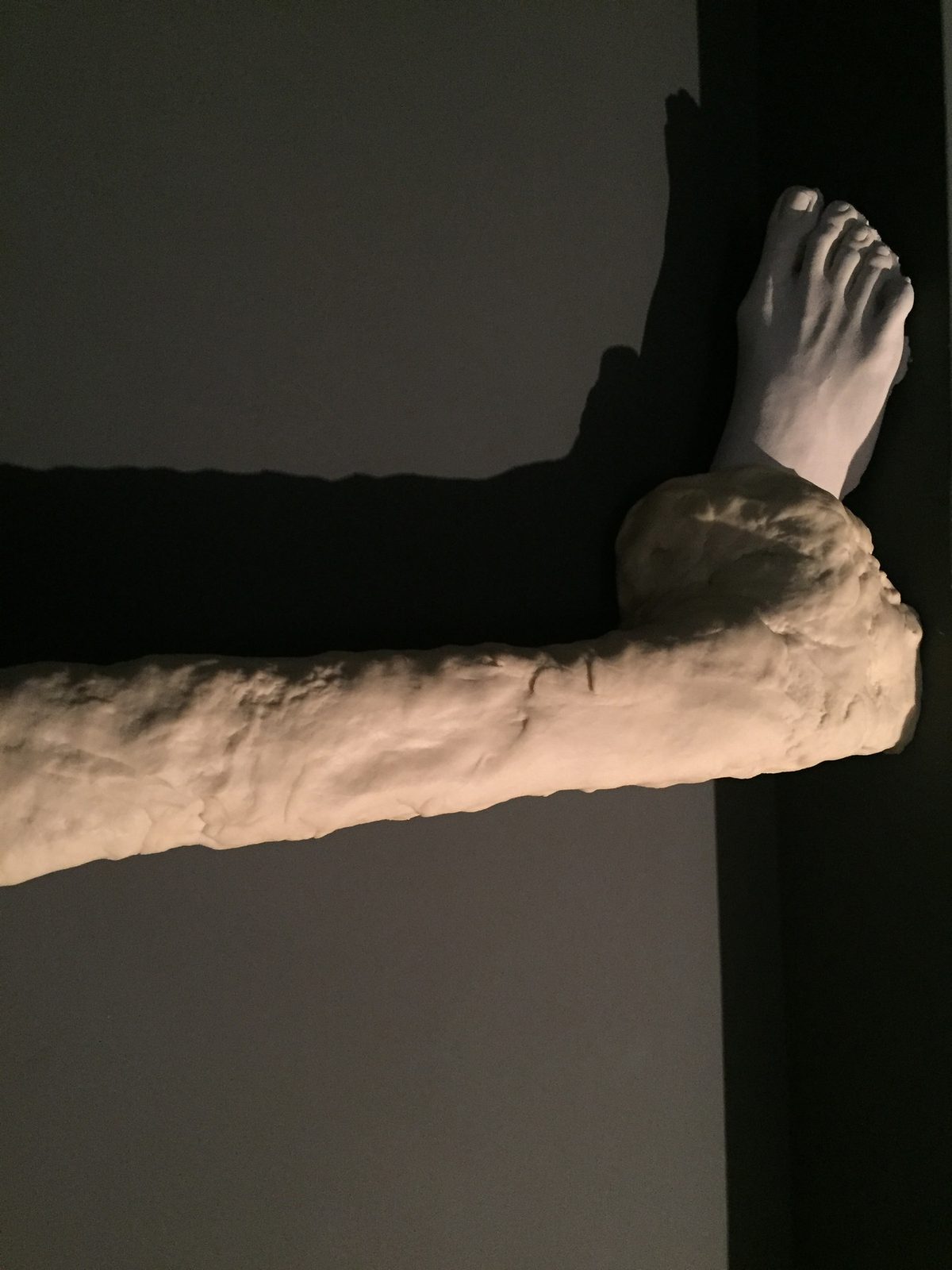 A cast white foot on a dough-wrapped beam meeting the corner of a wall