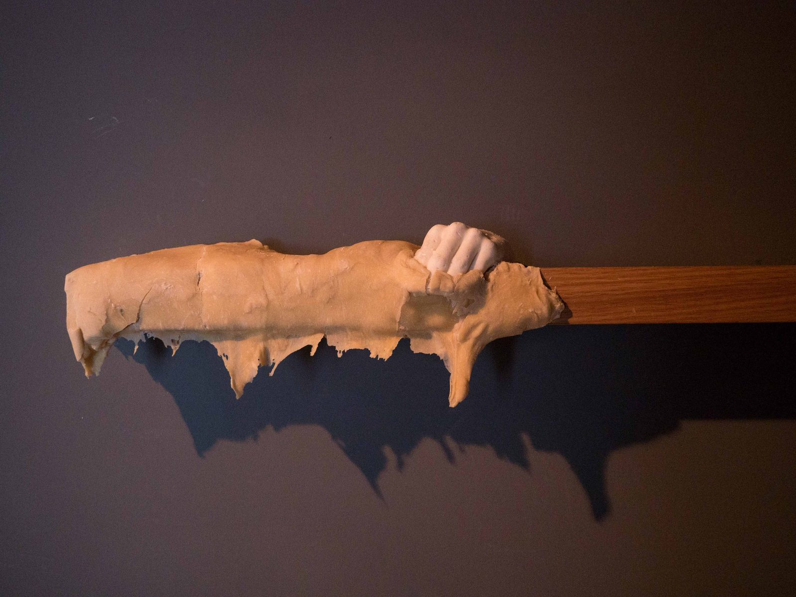 Dough dripping from a wooden beam with a cast hand at its end
