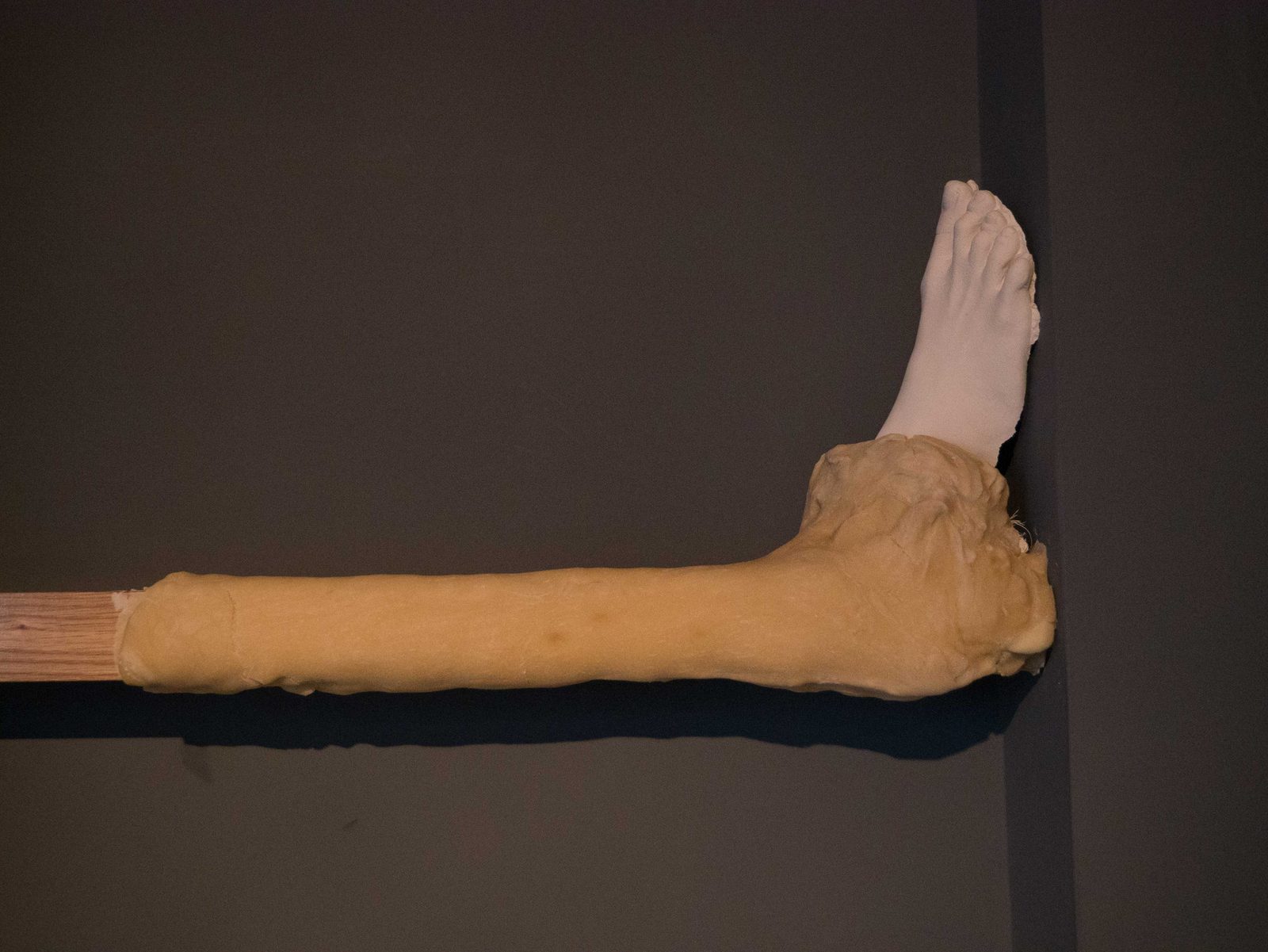 A cast foot at the end of a dough-covered beam against a grey wall