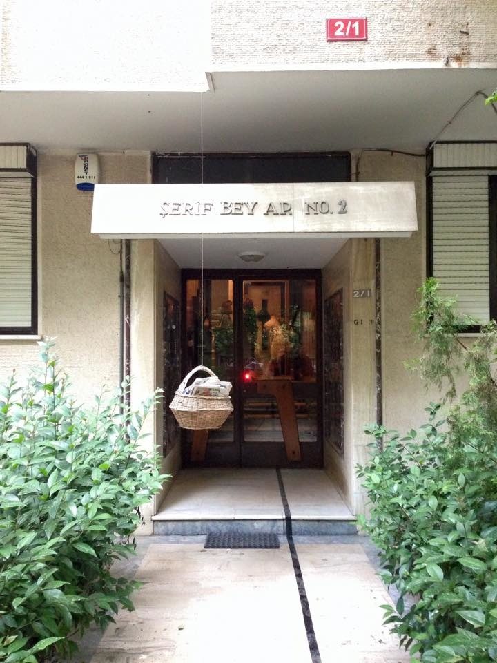 The entrance of Şerif Bey Apartmanı No. 2, a basket hanging in the doorway between potted plants